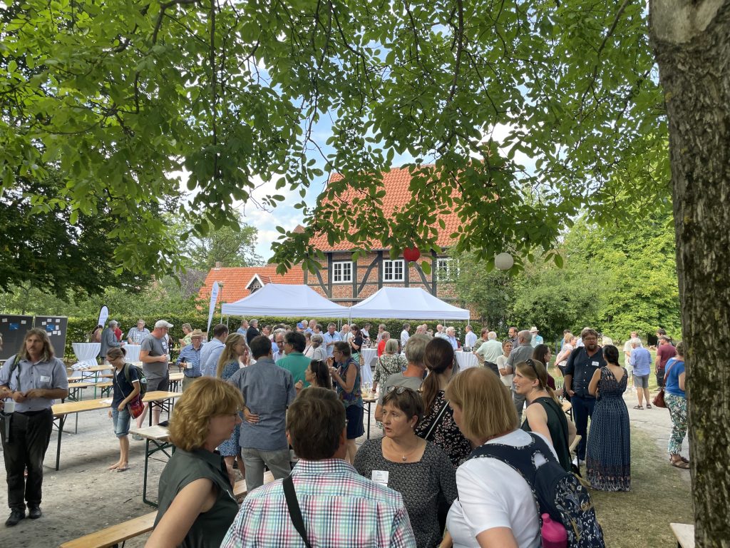 Viele Menschen, die im unter einem Baum und neben Zelten stehen und miteinander sprechen